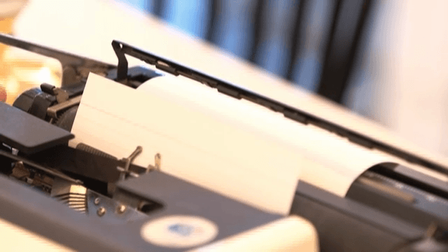 타자기에 종이를 끼워 넣는 손