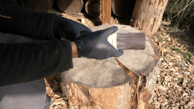 Sanding wooden piece holes on an outdoor workbench