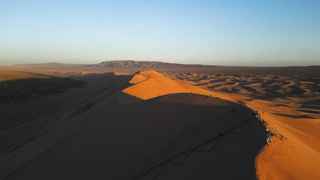 People on sand dunes at sunset