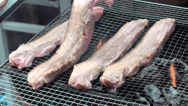 Grilling pork belly on a charcoal grill