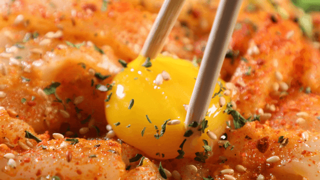 Chopsticks breaking egg yolk on water parsley and raw cuttlefish
