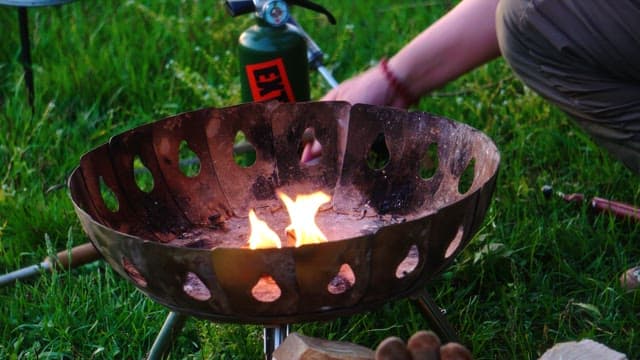 Lighting a fire with a torch and firewood on the lawn