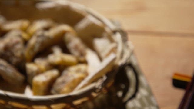 Deep-fried golden brown fried fish in a woven basket on a wooden table