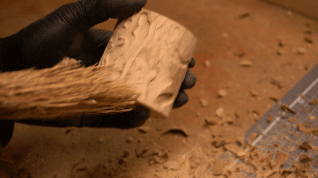 Artisan brushing dust off wooden piece in workshop