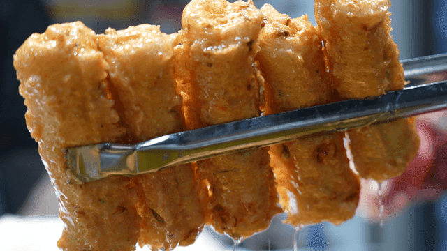 Fried fish cake lifted high with tongs