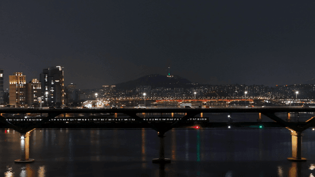 Cars and subways running on river against city backdrop