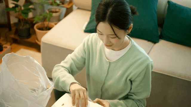 Woman opens box of chicken in her cozy living room.