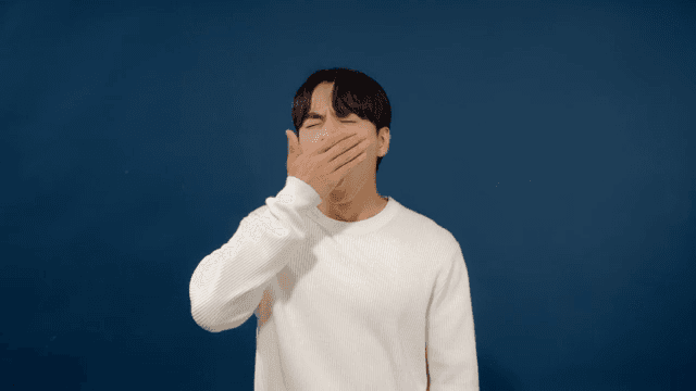 Sleepy man yawning wearing white sweater