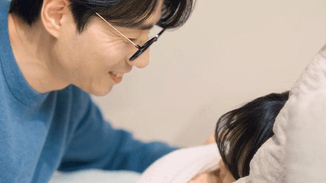 잠든 아이를 다정하게 쓰다듬는 아빠