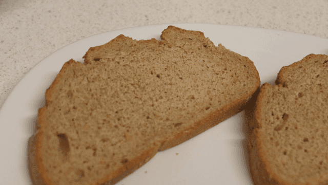 Piece of brown whole wheat bread placed on white plate