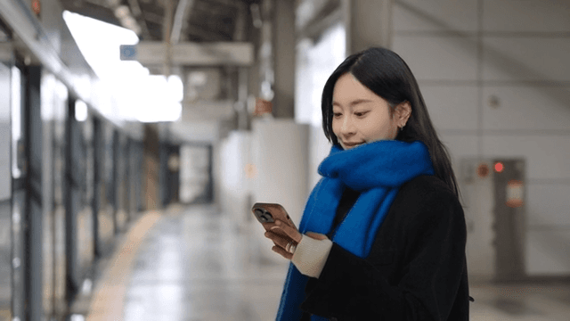 Woman using smartphone at a train station