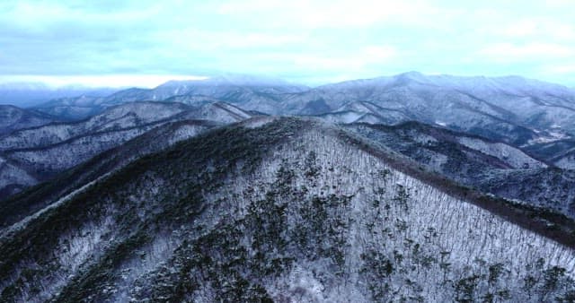 흐린 하늘 아래 광활하게 펼쳐진 눈 덮인 산