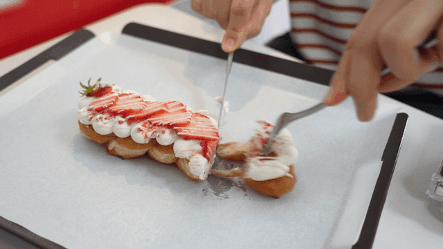 Hands cutting strawberry cream dessert with knife