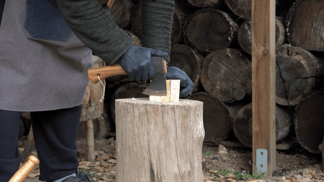 야외에서 도끼로 나무를 패는 사람