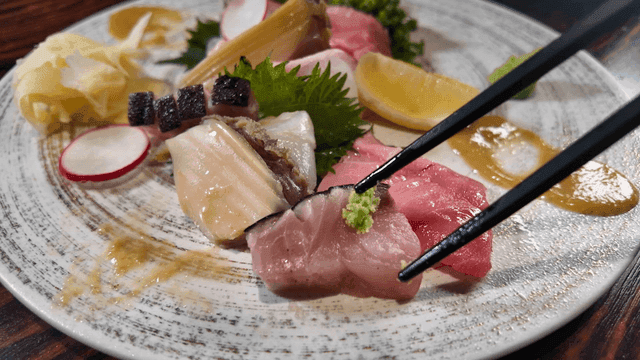 Assorted sashimi picked up with wasabi