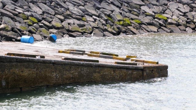 잔잔한 파도가 치는 초록색 이끼가 낀 바위 부두