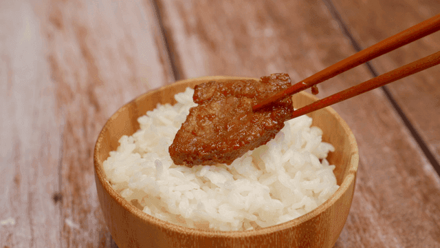 밥 위에 양념 고기 한 조각이 있는 그릇