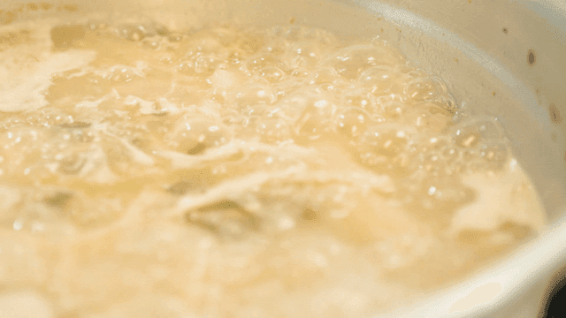 Whole chicken broth boiling in pot