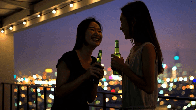 발코니에서 음료를 즐기는 두 친구