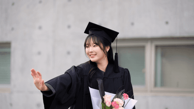 Graduates greeting with smiles and holding bouquets of flowers