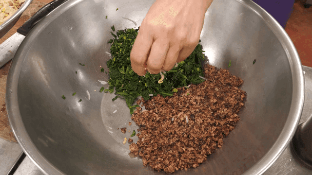 Bowl containing seasoned spinach and stir-fried minced shiitake mushrooms