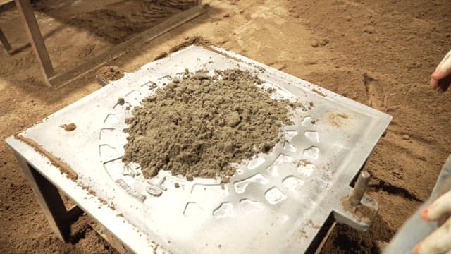 Person preparing sand mold for casting