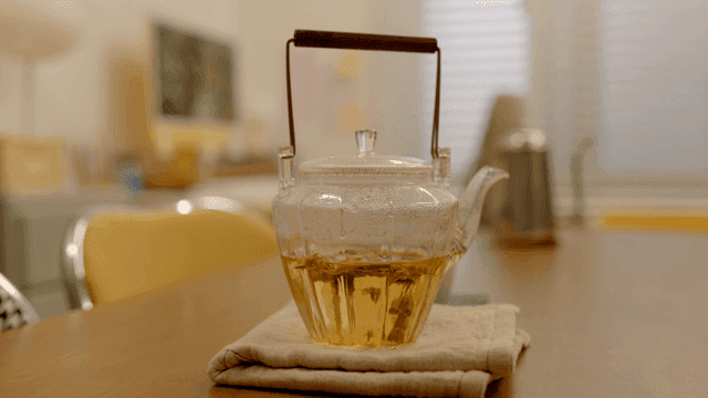 Glass teapot containing herbal tea on table.