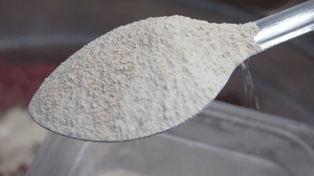 Spoon scooping white honey powder from container