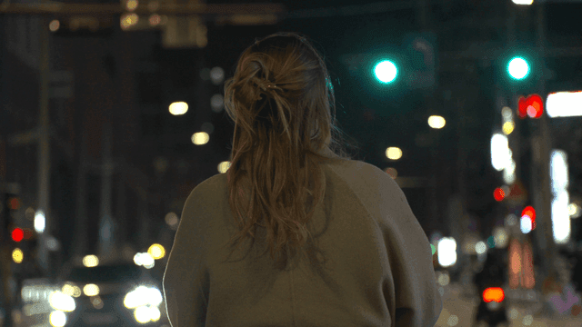 Back view of woman standing on busy road at night