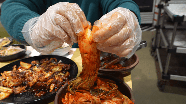 Person eating kimchi with his hands at table