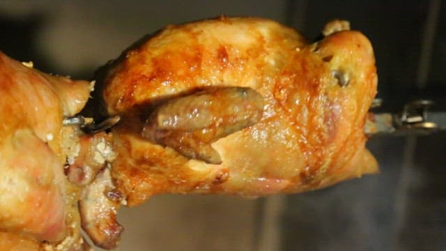 Rotisserie chicken roasting on a spit