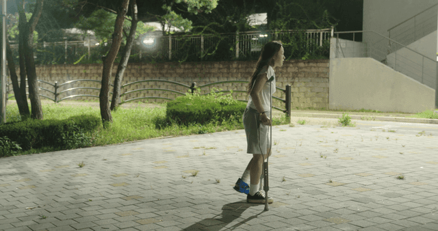 밤에 목발을 짚고 걷는 여성