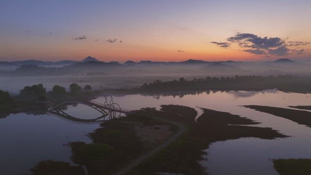 Serene river with misty mountain at sunset