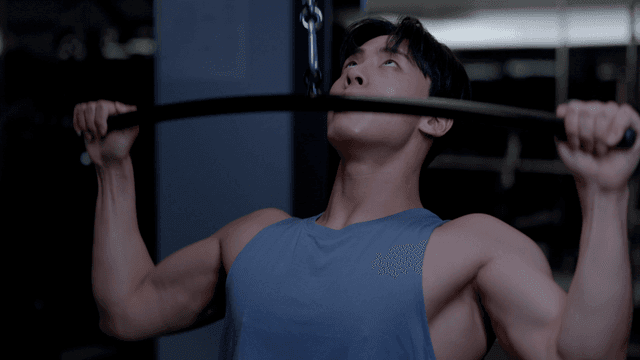 헬스장에서 랫플다운 기구로 어깨운동하는 젊은 남자