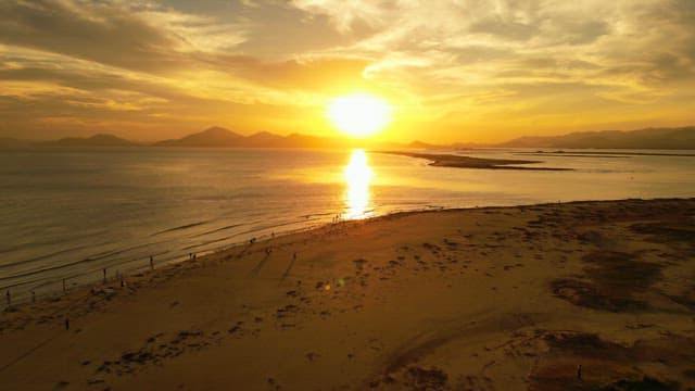 Sunset over a calm sea with distant mountains