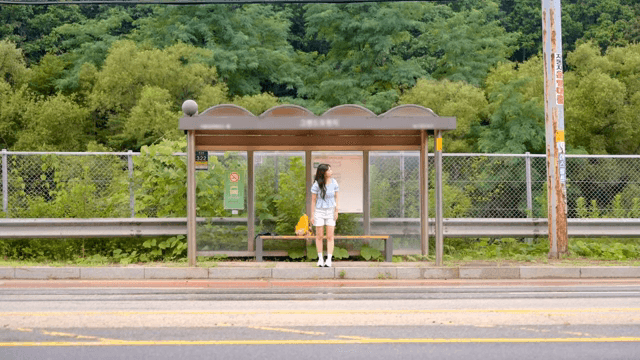 시골의 버스 정류장에서 기다리는 여성