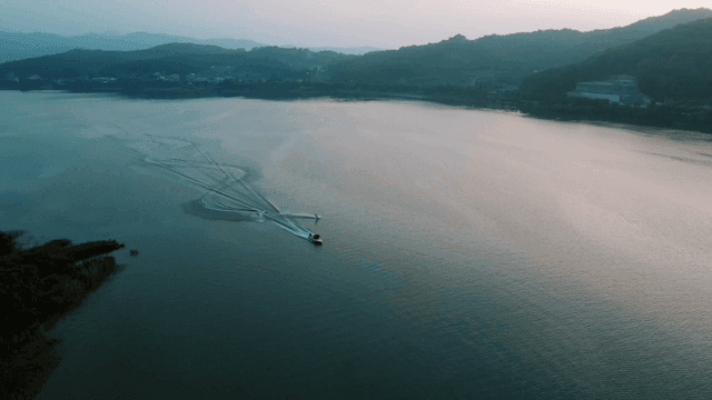 Boat water skiing creating waves on calm lake