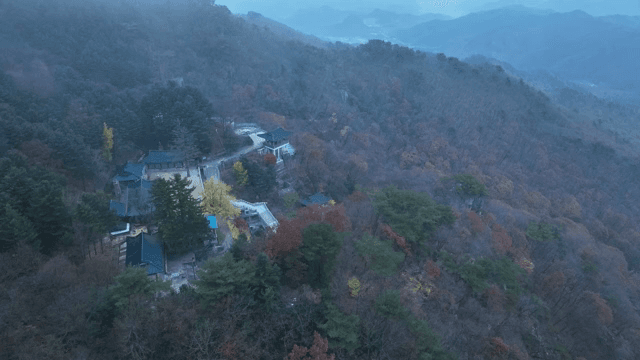 Misty mountain landscape with a distant hanok