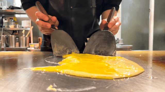Chef preparing an omelette on a hot grill