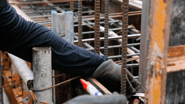 Worker marking steel bars at a construction site