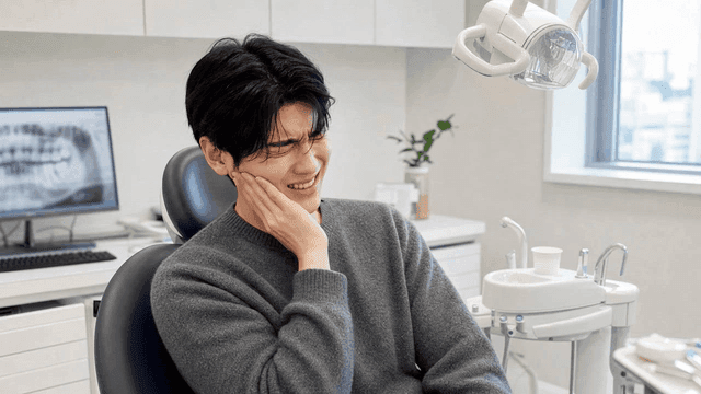 Young male patient suffering from toothache at dental clinic