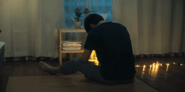 Back view of a man sitting on a lighted floor