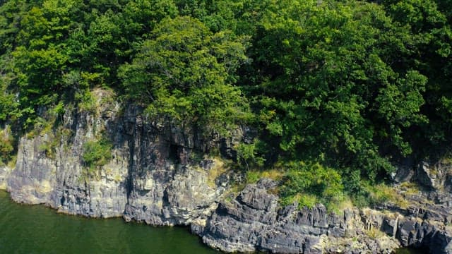 Lush green mountains by a serene river under a clear sky