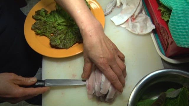 Preparing sliced raw scaled sardine on a bed of lettuce