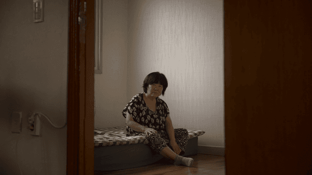 실내에서 침대에 앉아 있는 노인 여성