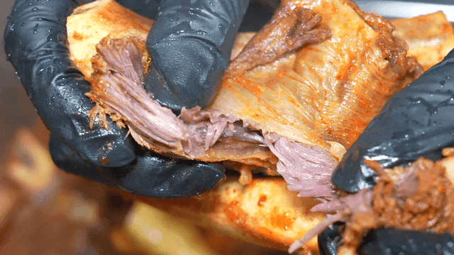Hands tearing apart seasoned braised beef short ribs