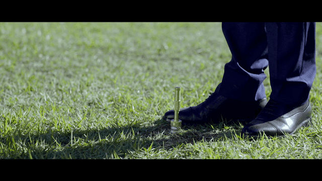 Person walking on grass next to sprinkler in field
