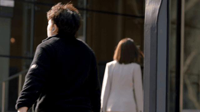 Back view of female office worker heading to work in glass building