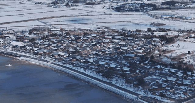 Snow-covered traditional Korean village next to tidal flat
