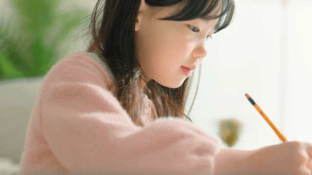 실내에서 글쓰기에 집중하는 어린 소녀